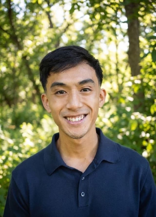 Joseph Low, smiling in front of sunlit greenery